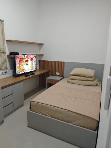 a bedroom with a bed and a desk with a television at Sukabumi Villa Mochi Private Jacuzzi in Sukabumi