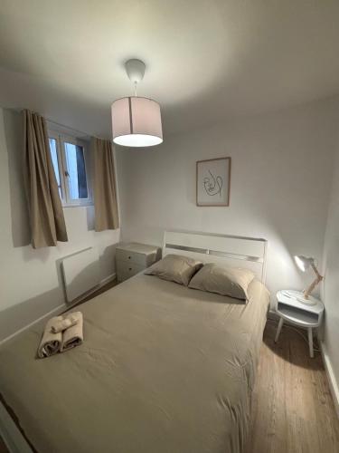 a white bedroom with a bed and a lamp at charmant appartement 4 pers hyper centre, au calme in Rouen