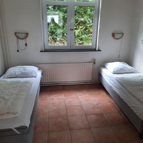 two beds in a room with a window at Slufterduin 80 in De Cocksdorp