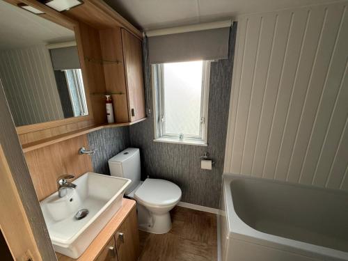a bathroom with a sink and a toilet and a mirror at Summer Meadows at Sandy Bay in North Seaton