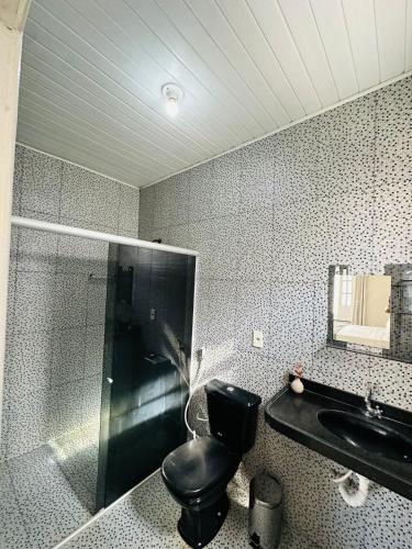 a bathroom with a black toilet and a sink at Casa da Lua in Barreirinhas