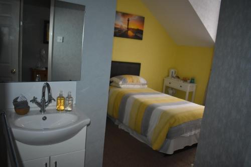 a bathroom with a sink and a bed in a room at The Phoenix Guest House in Scarborough