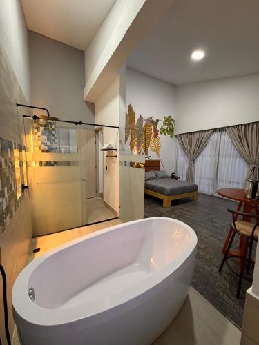 a large white tub in a bathroom with a bedroom at Hotel Campestre Alma Nativa in Calarcá