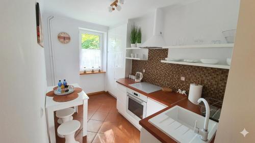a white kitchen with a sink and a counter at Apartament Motylek in Hajnówka