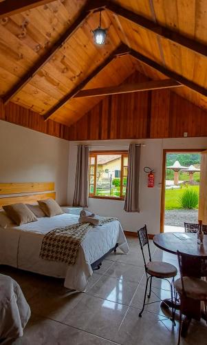 a bedroom with a large bed and a table at Pousada Rural Pavão - Suites e Chalés in Urubici