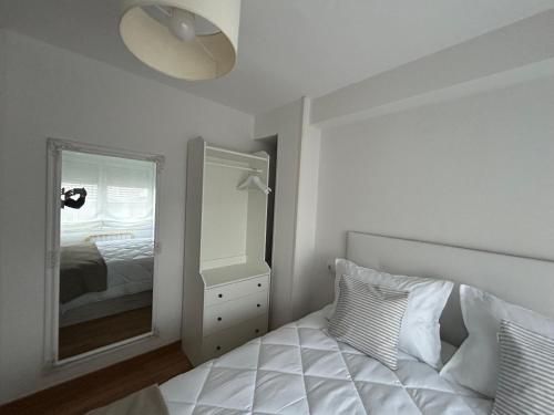 a white bedroom with a bed and a mirror at La Costa Suite in Gijón