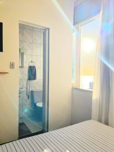 a bedroom with a glass door leading to a bathroom at Melhor Localização do Centro Histórico de Salvador in Salvador