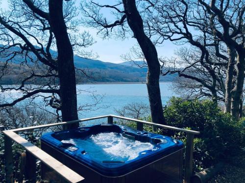 a jacuzzi tub with a view of a lake at Waterside Cader Cabin with Hot Tub in Barmouth
