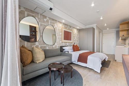 a bedroom with a bed and a couch and mirror at 5 Star Elegant Apartments, Ellipse, Waterfall City, Midrand, Johannesburg in Midrand