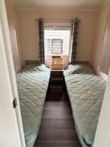 two beds in a small room with a window at Vakantiehuisje op 5 star kindercamping in Mariënberg