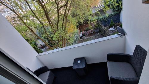 a balcony with two chairs and a window with trees at Viktoria's Appartment 2 in OB-Mitte in Oberhausen