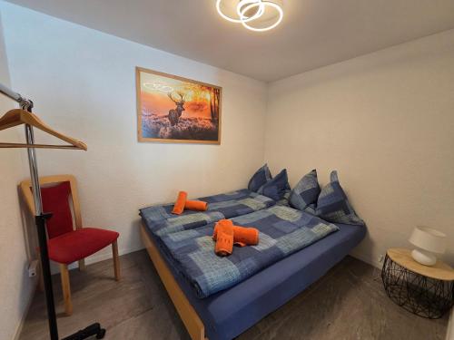 a bedroom with a blue bed and a red chair at Lilo's one-room apartment in Beatenberg