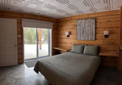 a bedroom with a bed with a wooden wall at Chalet L'Orée Étoilée in La Tuque