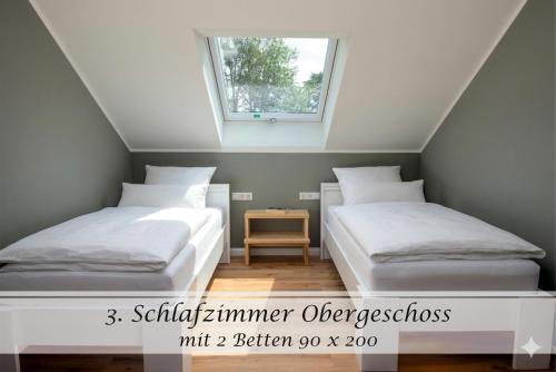 two beds in a room with a window at Ferienwohnung Feinheit - Gulfhof nahe Greetsiel mit Sauna, Garten & 3 Schlafzimmern in Krummhörn