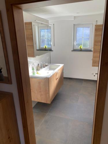 a bathroom with a white sink and two windows at Ferienwohnung unterm Äpflet in Furth im Wald