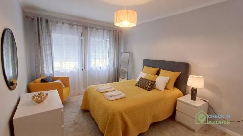 a bedroom with a large bed with a yellow blanket at Cantinho da Bea Guest House in Angra do Heroísmo