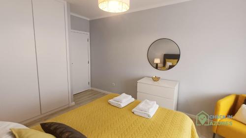 a bedroom with a yellow bed and a mirror at Cantinho da Bea Guest House in Angra do Heroísmo