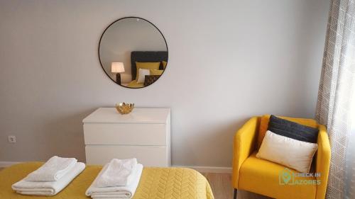 a bedroom with a yellow chair and a mirror at Cantinho da Bea Guest House in Angra do Heroísmo