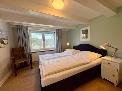 a bedroom with a large bed and a window at Altes Friesenhaus West in Morsum