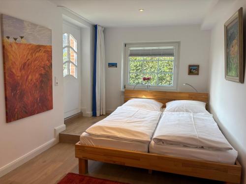 a bedroom with a bed in a room with a window at Altes Friesenhaus Scheune in Morsum