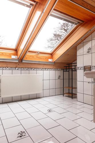 an attic bathroom with a skylight and white tiling at Landhausvilla Watzmannblick in Saaldorf-Surheim