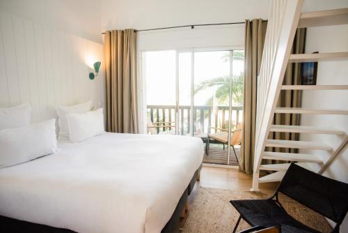 a bedroom with a large white bed and a balcony at Les Hortensias du Lac - Fontenille Collection in Hossegor