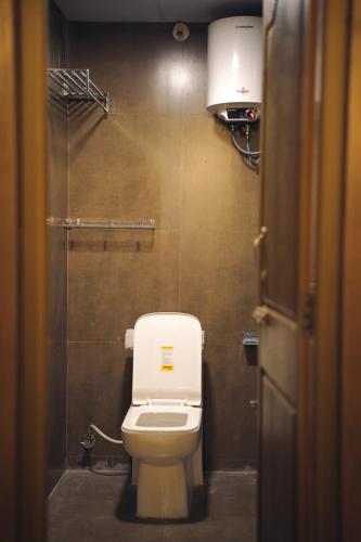 a bathroom with a white toilet and a light at Aostel in Chennai