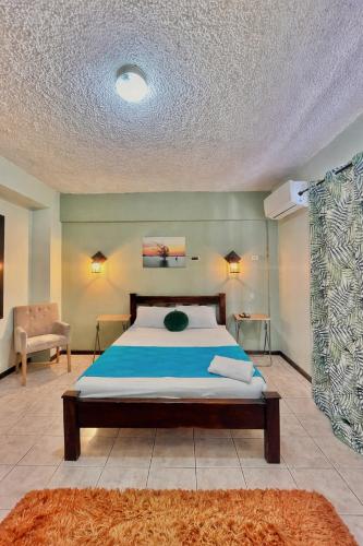 a bedroom with a large bed with a blue blanket at Hotel Miami CR in Puerto Limón