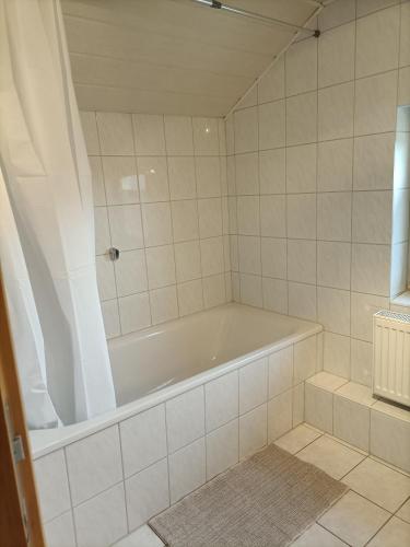 a white bath tub in a white tiled bathroom at Gästezimmer Kalletal in Kalletal