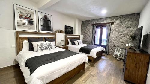 a bedroom with two beds and a stone wall at Anae en ValQuirico in Santeagueda