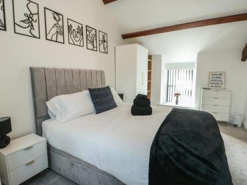 a bedroom with a large white bed with a black bag on it at Rhows in Llanfairpwllgwyngyll