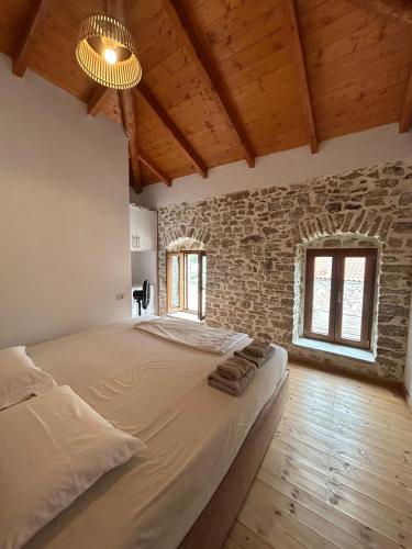 a bedroom with a large bed in a brick wall at Vila, Upper Qeparo in Qeparoi i Sipërm