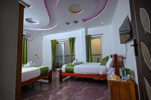 a bedroom with two beds and a flat screen tv at Fairy Beach House - DK Resort in Pondicherry