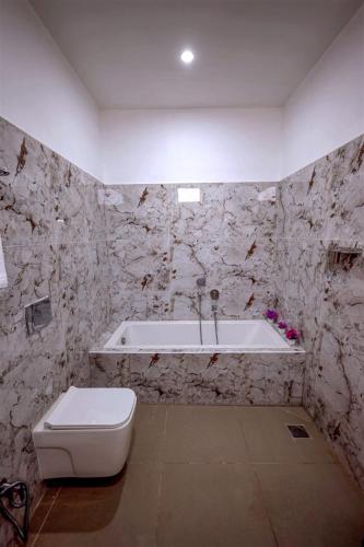 a bathroom with a toilet and a bath tub at Fairy Beach House - DK Resort in Pondicherry