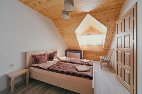 a bedroom with a bed and a wooden ceiling at Kaimo turizmo sodyba "Ąžuola" in Vainutas