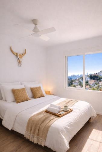 a white bedroom with a large bed with a window at Casa MuMa in Calpe
