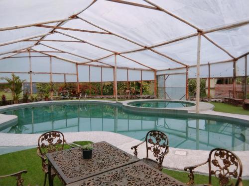 a pool with a table and chairs in front of a tent at Las Orquídeas Runtun Lodge in Baños
