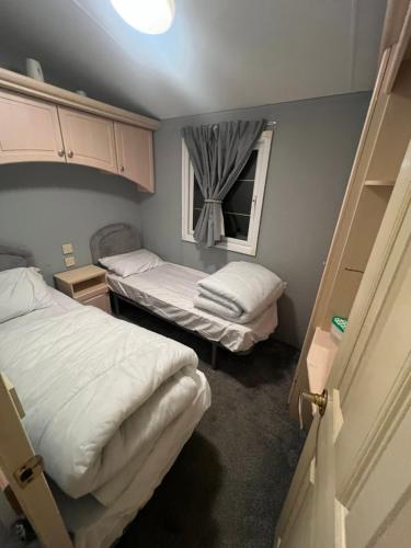 a small bedroom with two beds and a window at Millfields caravan park I9 in Skegness