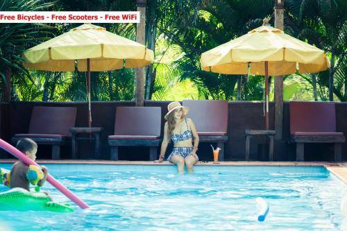 a woman sitting in the water in a swimming pool at Baanpong Lodge in San Kamphaeng