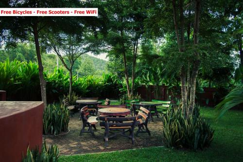 a group of tables and chairs in a garden at Baanpong Lodge in San Kamphaeng