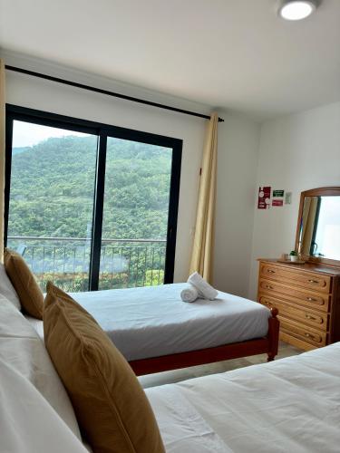 two beds in a room with a large window at Seaside & Levada Escape in Machico