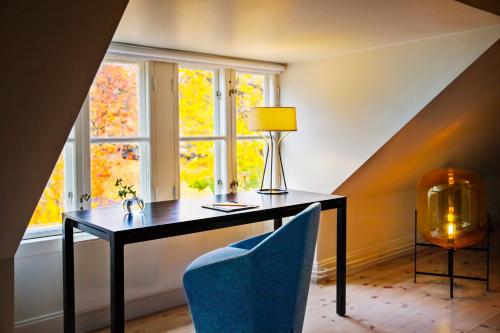 a desk with a lamp and a chair in front of a window at Hotel Skeppsholmen, Stockholm, a Member of Design Hotels in Stockholm