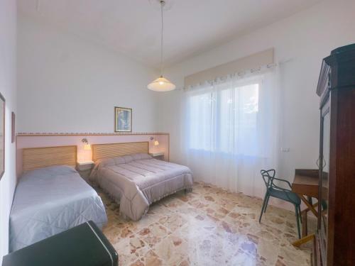 a bedroom with two beds and a table and a chair at Affitta camere ALMA MATER in Castrignano del Capo