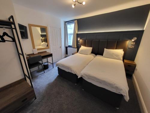 a bedroom with two beds and a desk and a mirror at At Caledonia in Douglas