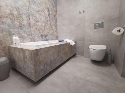 a bathroom with a bath tub and a toilet at Sunset Terrace Wrocław Stadion in Wrocław