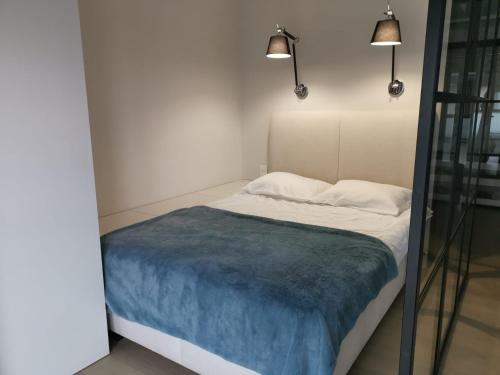 a bed with a blue blanket and two pillows at Sunset Terrace Wrocław Stadion in Wrocław