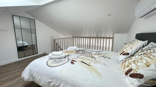a bedroom with a bed with white sheets and a mirror at Les Myosotis in Vernon