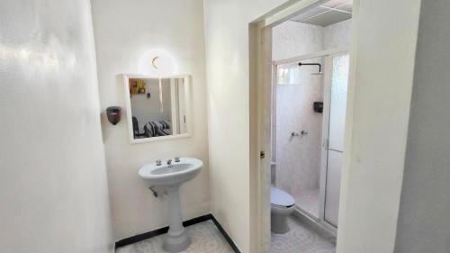 a white bathroom with a sink and a toilet at Hotel Catalina in Torreón