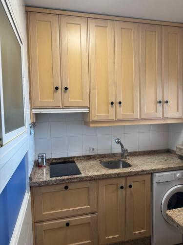 una cucina con mobili in legno e un lavello di Apartaments Bastion a Torremolinos