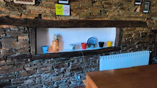 a brick wall with a shelf with colorful vases on it at Albergue Val de Samos in Samos